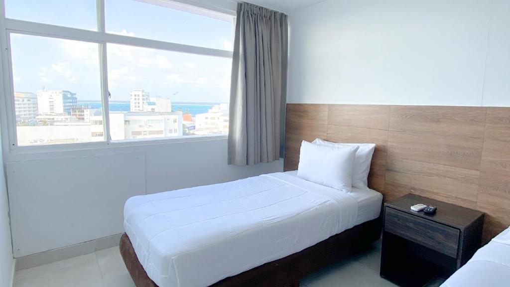 una camera con un letto bianco e una grande finestra di On Vacation Tower a San Andrés