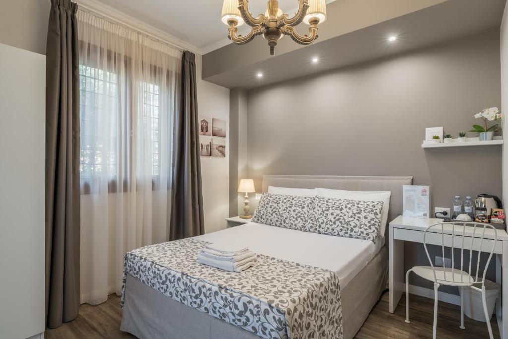 a bedroom with a bed and a table and a chandelier at B&B L'Ulivo Fiumicino in Fiumicino