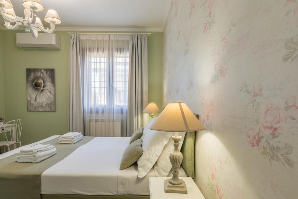 a bedroom with a bed with a lamp and a window at B&B L'Ulivo Fiumicino in Fiumicino