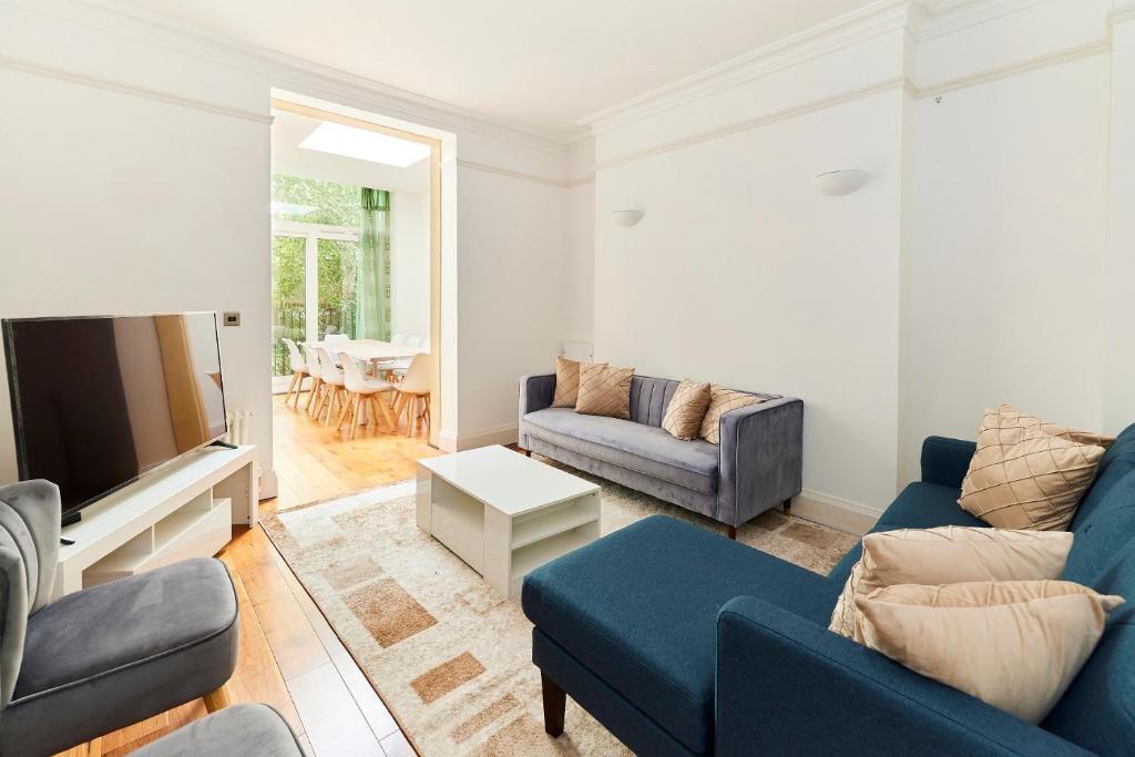 a living room with a blue couch and a tv at The Woolwich Retreat - Enticing 5BDR House with Parking in Woolwich