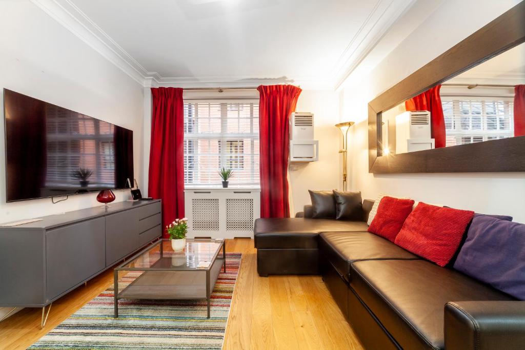 a living room with a brown couch and red curtains at Lovely 1BDR flat in the Heart of London - Mayfair in London