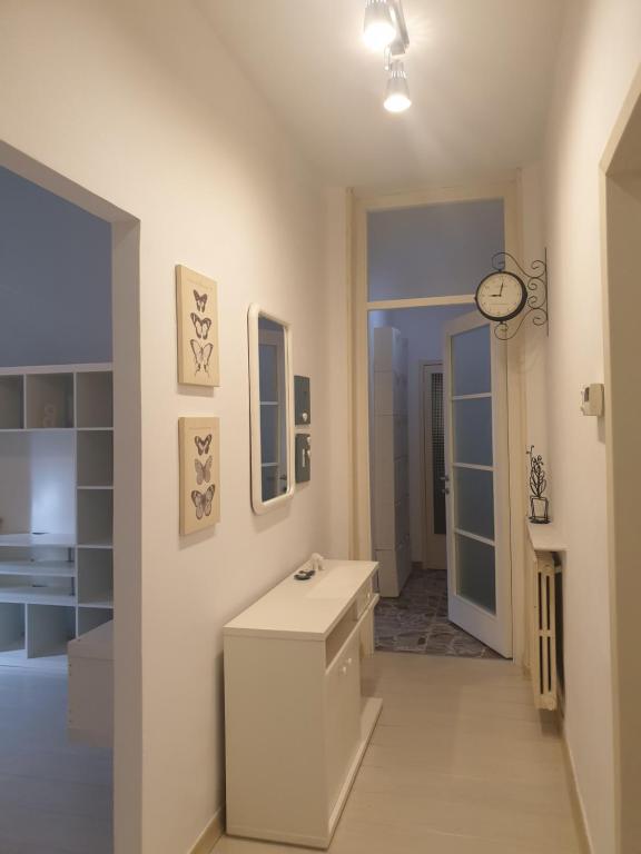 ein weißes Badezimmer mit einem Waschbecken und einer Uhr an der Wand in der Unterkunft Cleo Tulipano in Falconara Marittima