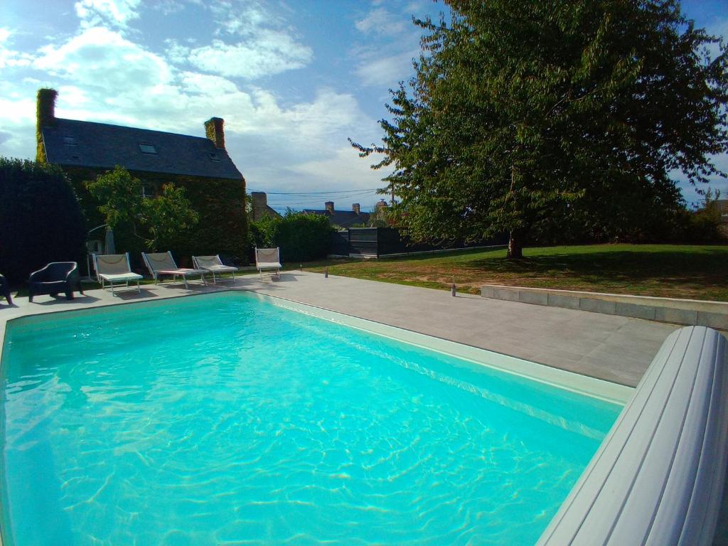 een groot blauw zwembad met stoelen en een huis bij DOMAINE DES TISSEYS vue sur le Mont St Michel in Dragey