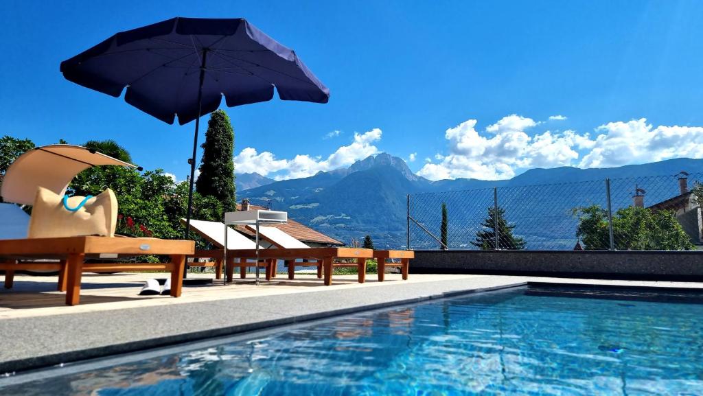 ein Schwimmbecken mit Stühlen und einem Sonnenschirm neben einem Pool in der Unterkunft MENA Guesthouse in Marling