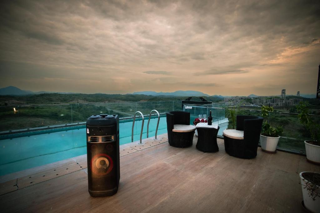 a balcony with tables and stools on top of a building at Amizunie's Boutique Hotel by SSAZ Hospitality in Udaipur