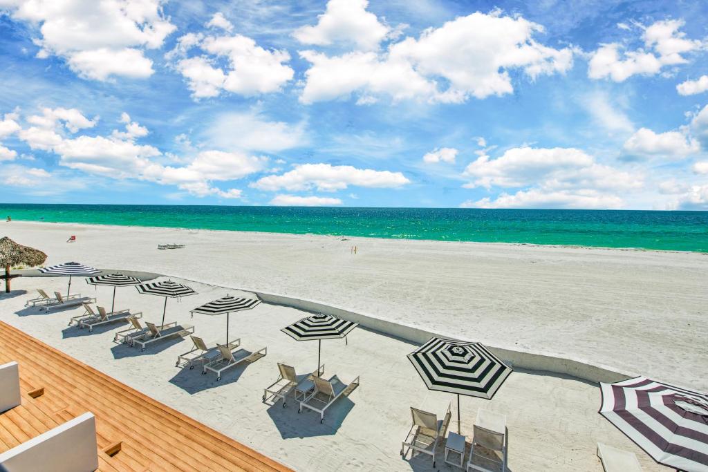 a beach with chairs and umbrellas and the ocean at Seaside At Anna Maria Island Inn in Bradenton Beach