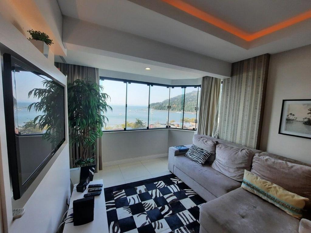 a living room with a couch and a large window at 3 Suítes Linda Vista da Orla de BC a 50m da Praia in Balneário Camboriú