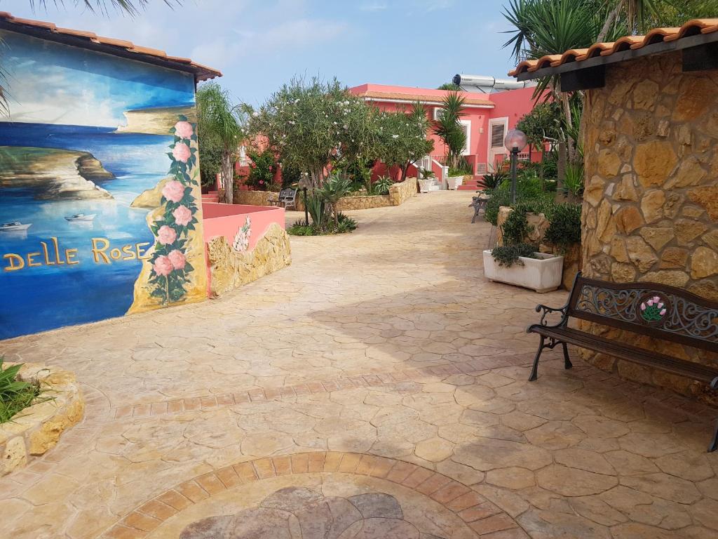 um banco sentado ao lado de uma parede com uma pintura em Residence Villa delle Rose em Lampedusa