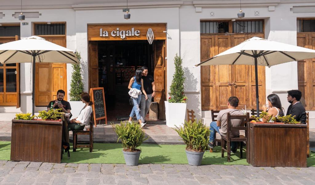 un grupo de personas sentadas en las mesas fuera de un restaurante en Hostal Restaurant La Cigale en Cuenca