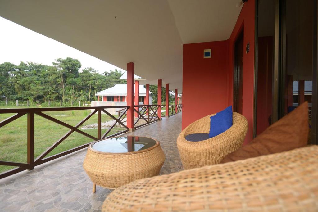 een patio met rieten stoelen, een tafel en een balkon bij Villa de hollong in Mādāri Hāt