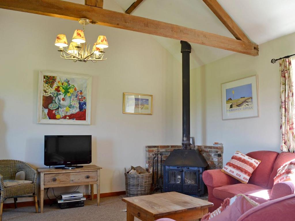 a living room with a fireplace and a tv at The Cart Shed - E1768 in Westleton