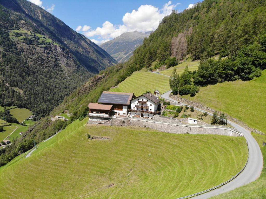 a house on a hill in a field with a road at Unterversanthof - Große Ferienwohnung für bis zu 6 Personen in Naturno