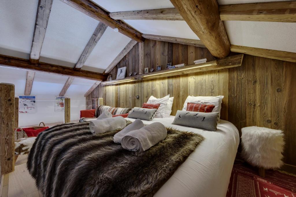 a large bed in a room with wooden walls at Appartement esprit chalet - splendide vue montagne in Val-d'Isère