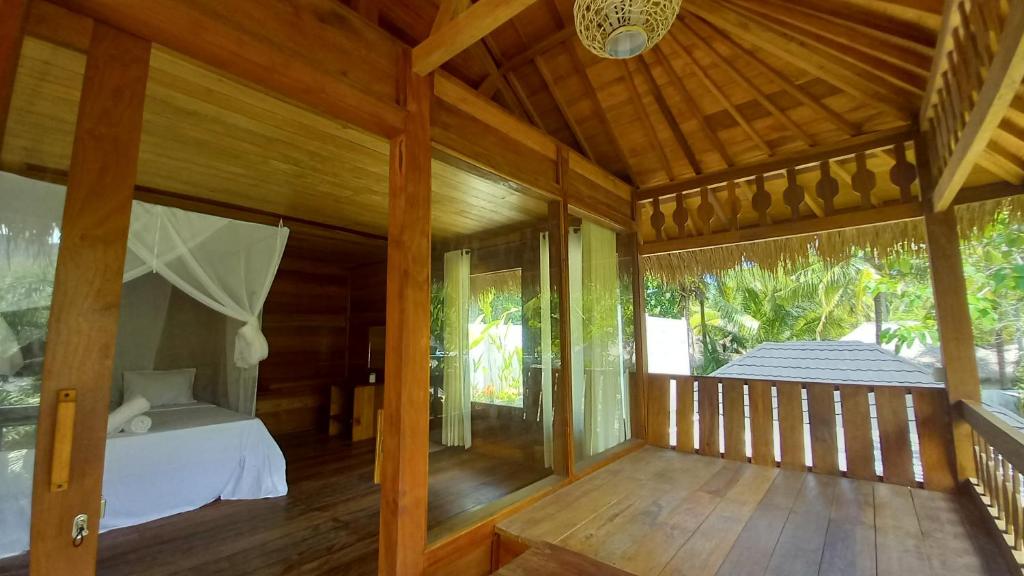 a room with a bed on a wooden porch at Palm Green Hotel in Kuta Lombok