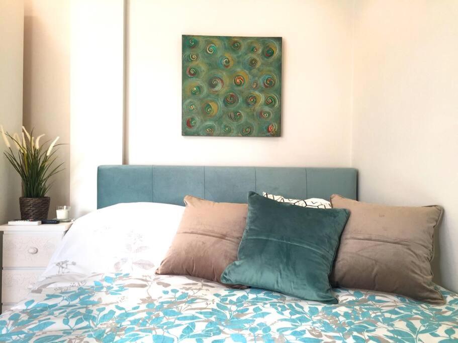 a bed with a blue head board with pillows on it at Emerald Mini Suite:Your deluxe studio in Kalamaria in Thessaloniki