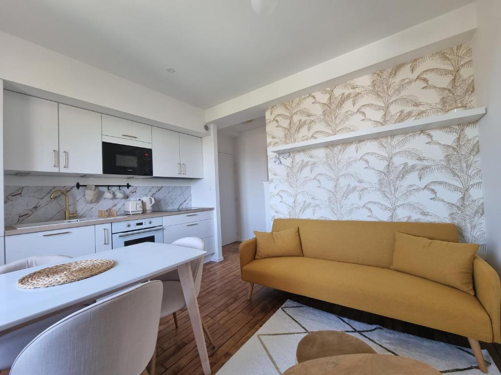 ein Wohnzimmer mit einem gelben Sofa und einer Küche in der Unterkunft Le Reflet Papillon by Madame Conciergerie in Bruz