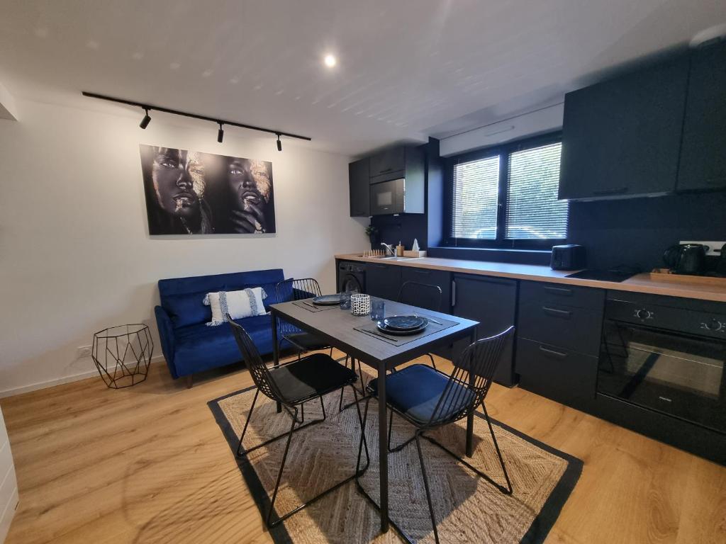 uma cozinha com armários azuis e uma mesa e cadeiras em L'Or Noir by Madame Conciergerie em Bruz