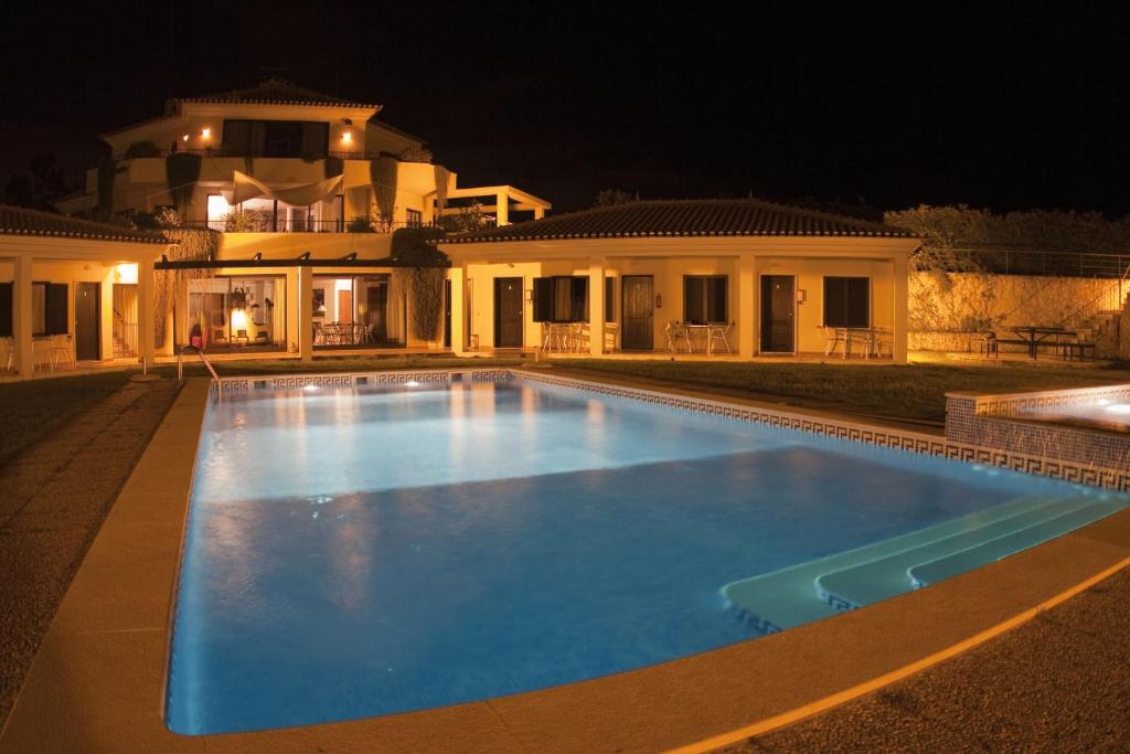 a swimming pool in front of a house at night at Quinta Dos Amarelos no Meco in Aldeia do Meco