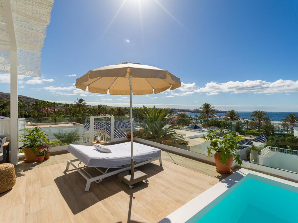 un patio con sombrilla, mesa y piscina en Pasitoblanco Porto Mare 7 Seaview Villa private heated pool, en Pasito Blanco