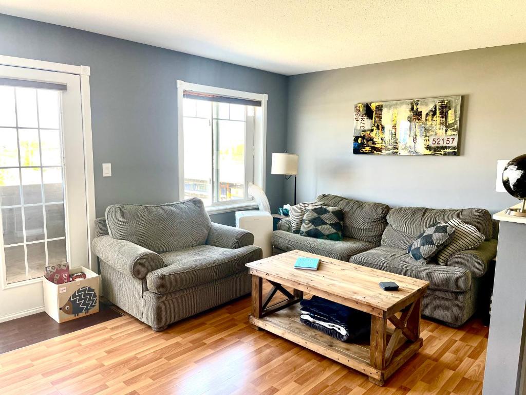 a living room with two couches and a coffee table at Top Floor Riverfront Condo with Stellar Sunsets! in Fort McMurray