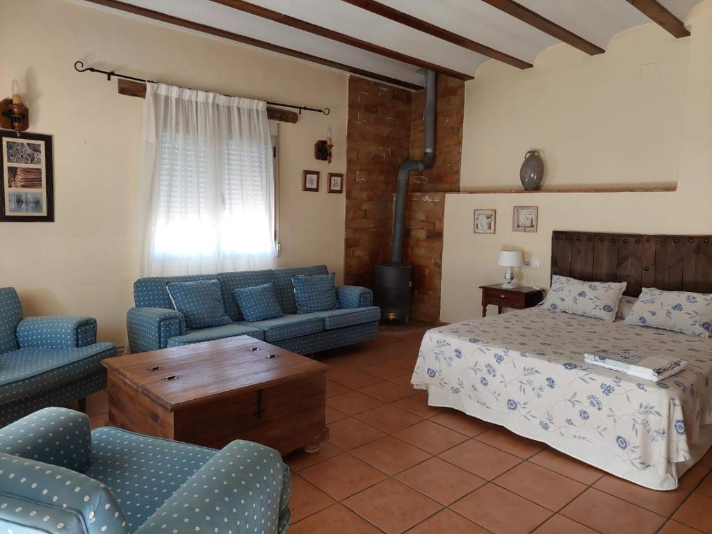 a bedroom with a bed and a couch and chairs at Casa Rural POSADA DEL JUCAR in La Gila