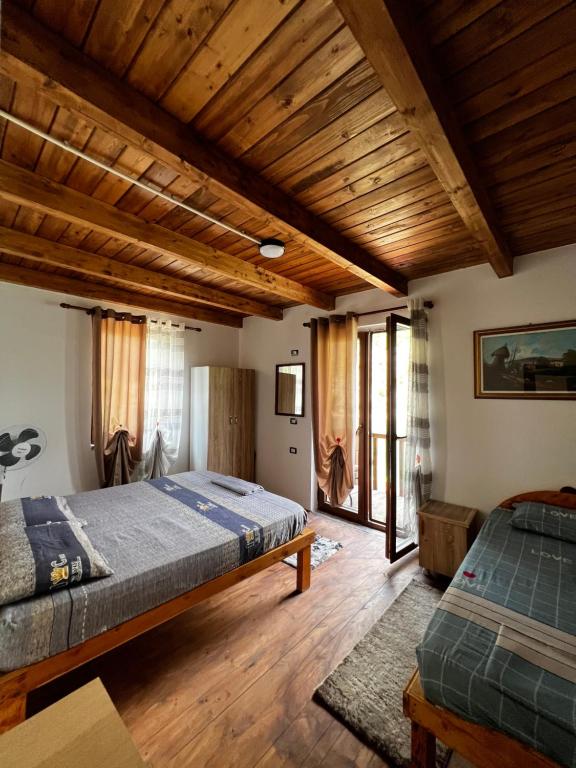 sypialnia z 2 łóżkami i drewnianym sufitem w obiekcie Guest House Aprripe Guri w mieście Fierzë