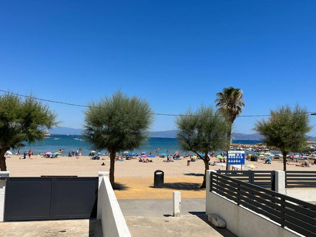 een strand met palmbomen en mensen op het strand bij Apartamento en la playa. Free Parking. Free WiFi in L'Escala