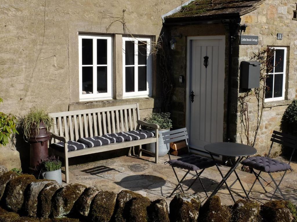 a bench in front of a house with a table and chairs at Little Brook Cottage in Hebden