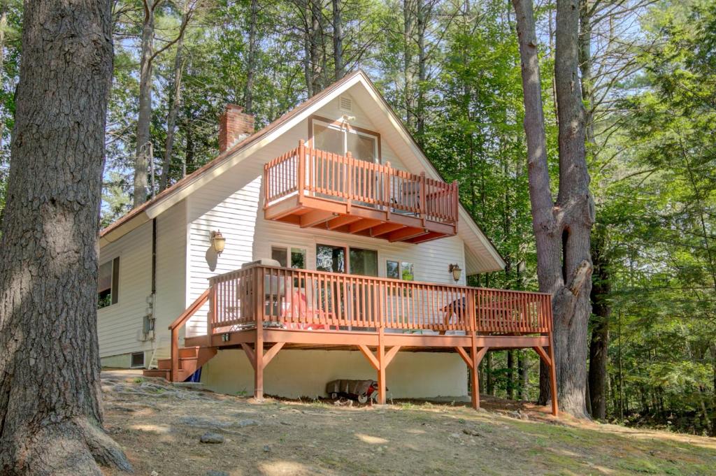 una casa con una gran terraza en el bosque en Gunstock Getaway, en Gilford