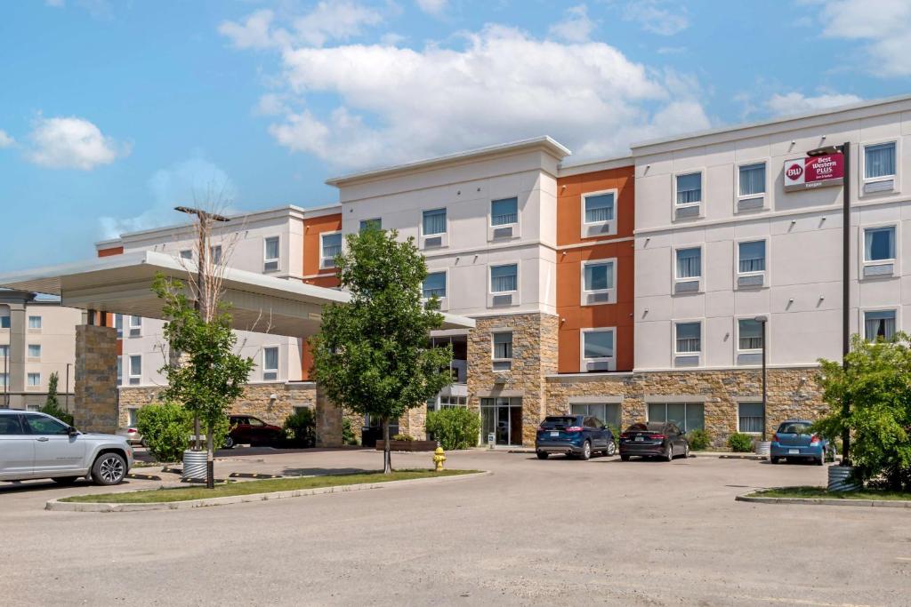 an apartment building with cars parked in a parking lot at Best Western Plus Eastgate Inn & Suites in Regina