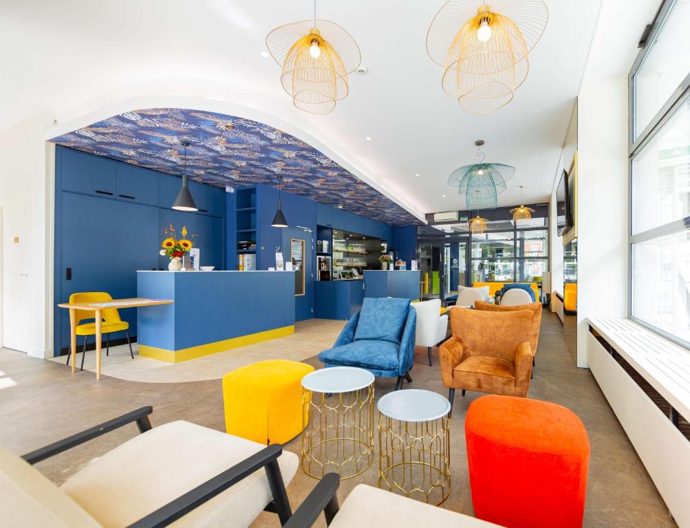 um restaurante com cadeiras e mesas coloridas numa sala em Best Western Mulhouse Salvator Centre em Mulhouse