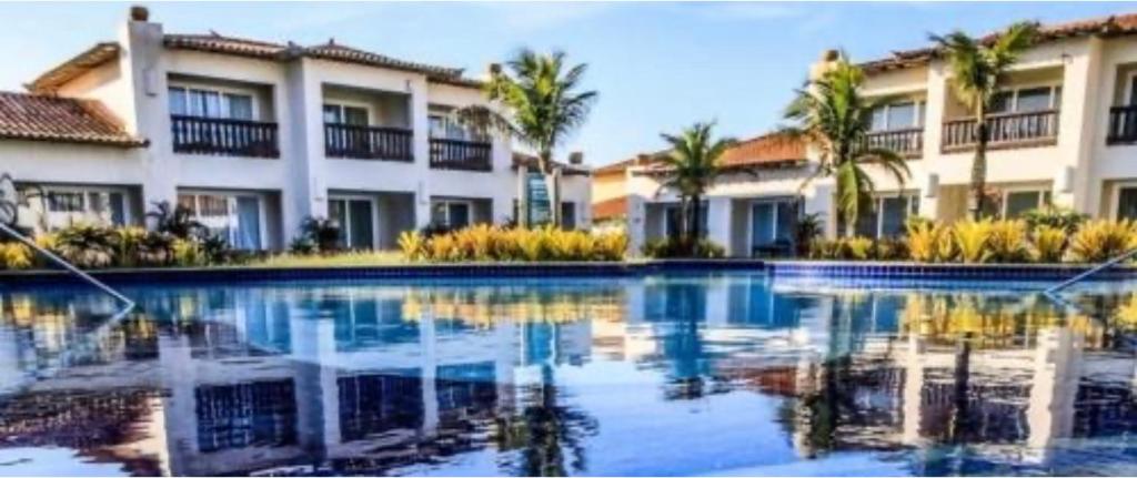 una piscina di fronte a un edificio con palme di Buzios Beach Resort Super Luxo Residencial 2501 e 2502 a Búzios