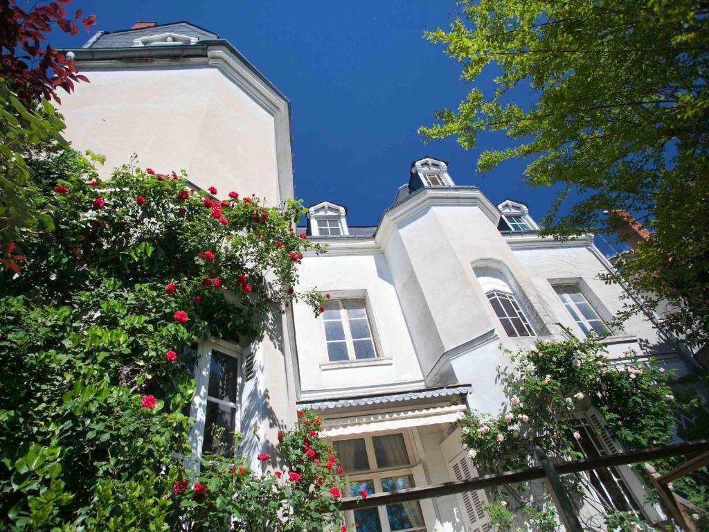 een wit gebouw met bloemen ervoor bij La Maison Jules in Tours