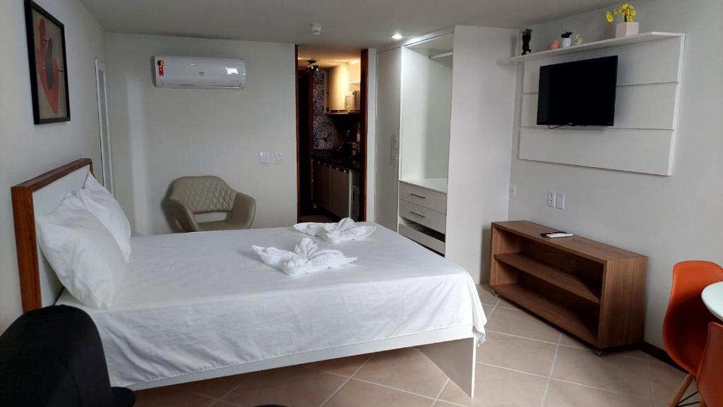 a bedroom with a white bed and a television at Victória Marina Flat in Salvador