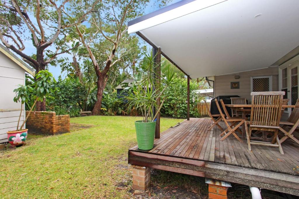 - une terrasse en bois avec une table et des chaises dans la cour dans l'établissement Beach Shack, à Hawks Nest