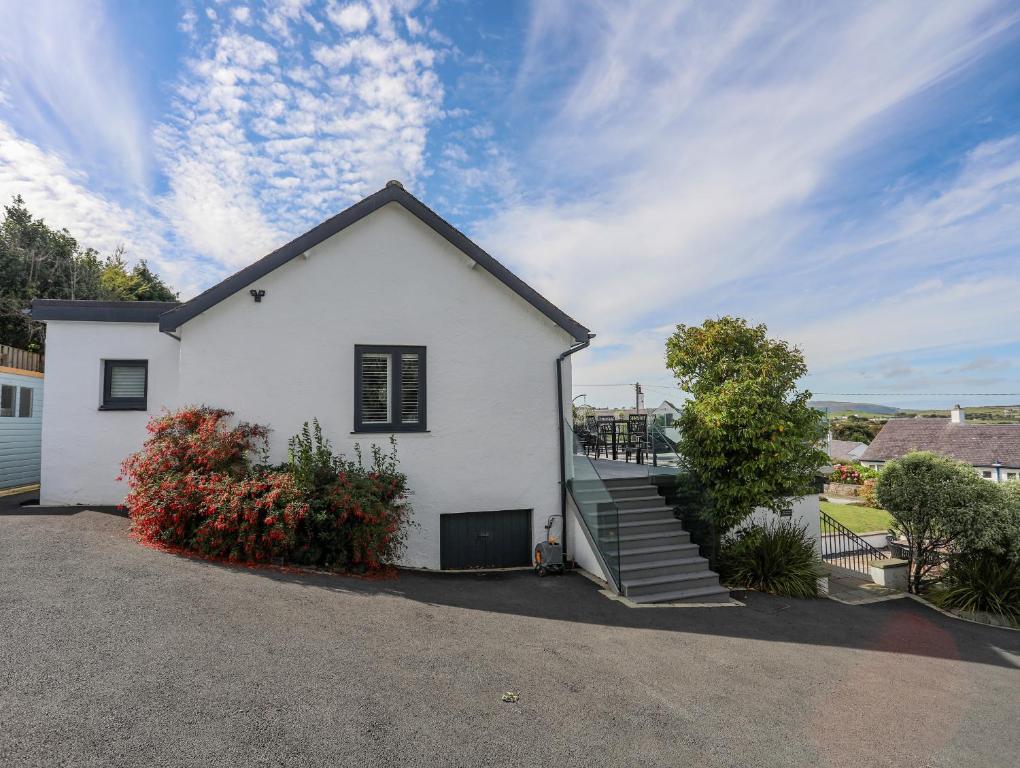a white house with stairs in a driveway at Trem Y Borth Apartment in Abersoch