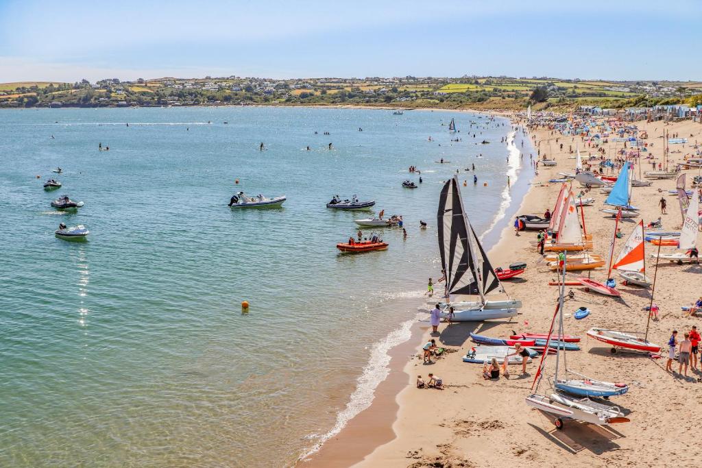 a group of people on a beach with boats in the water at Trem Y Borth Apartment in Abersoch