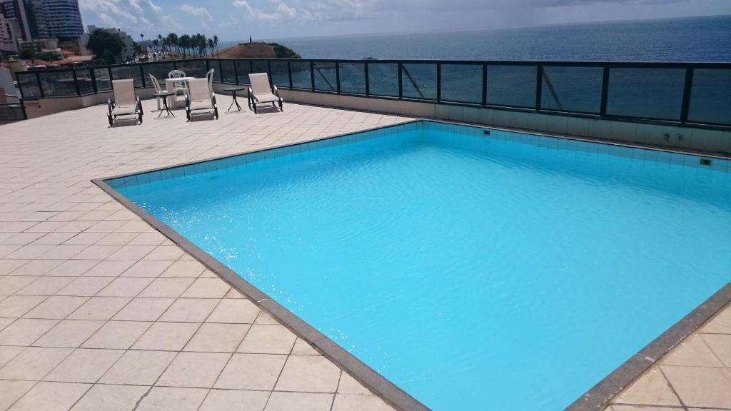 a large blue swimming pool on top of a building at Farol Barra Flat in Salvador