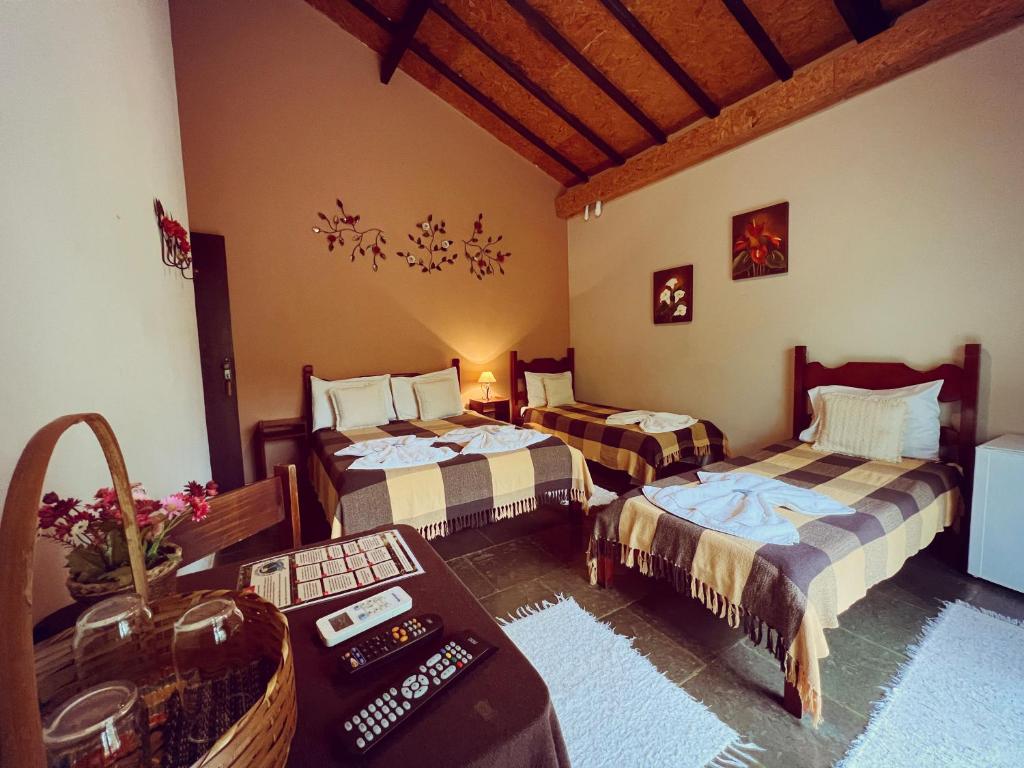 a living room with two beds and a table at Sarandy Hotel Eco Parque in Paraíba do Sul