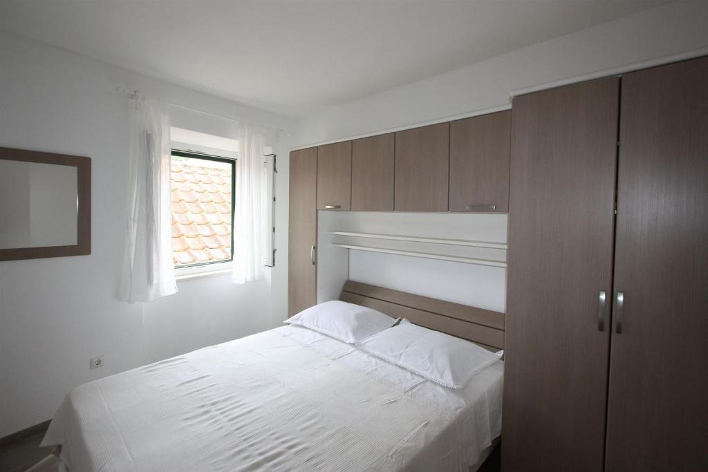 een slaapkamer met een wit bed en een raam bij Apartments Sonja in Pučišća