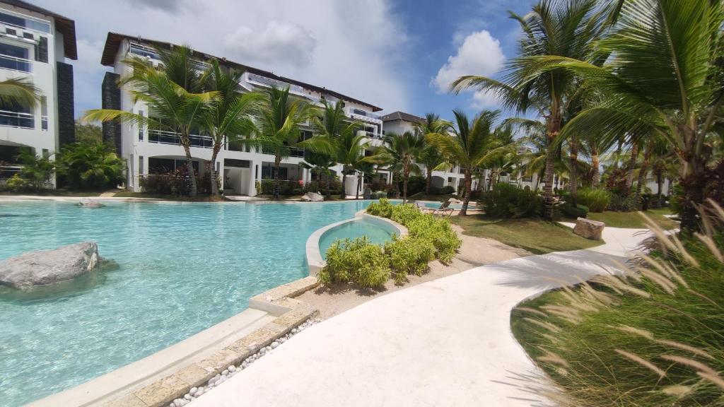 a swimming pool in front of a building with palm trees at Beautiful Apartment in Estrella Dominicus Bayahibe in Bayahibe