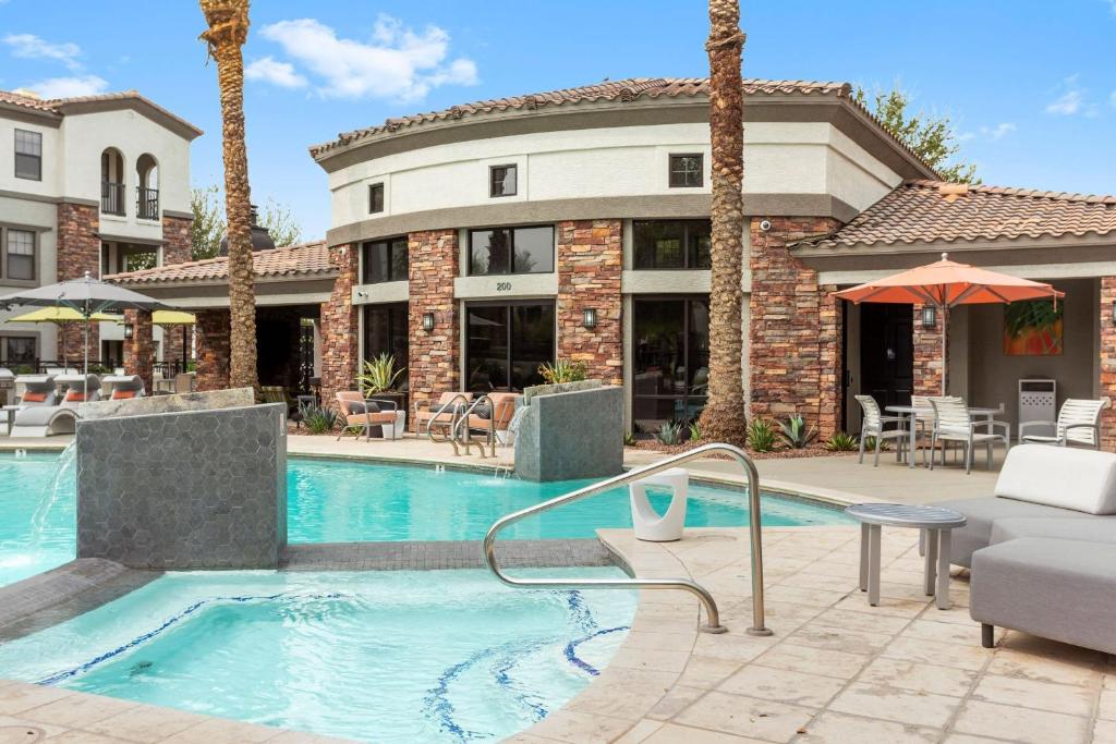 a swimming pool in front of a building with palm trees at CozySuites Glendale by the stadium with pool 01 in Glendale