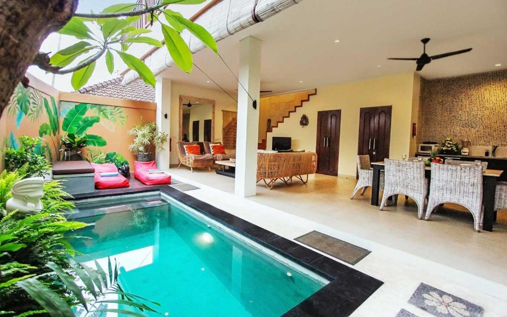 a villa with a swimming pool and a living room at Aroha Boutique Villas in Seminyak