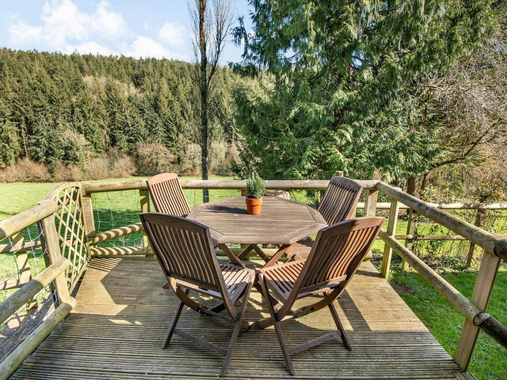 eine Holzterrasse mit einem Tisch und 2 Stühlen in der Unterkunft Maple Tree Cottage in Branscombe