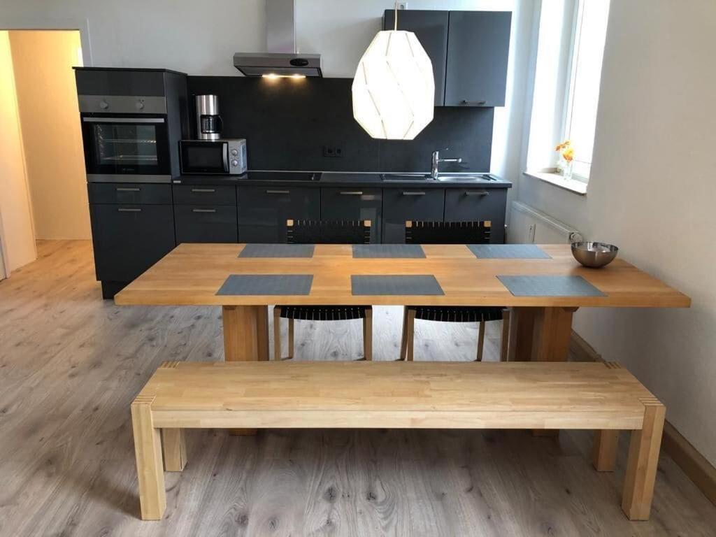 una cocina con mesa de madera y una cocina con armarios negros en studio m - Stylish Central City Business Apartment for 5 guests, en Düsseldorf