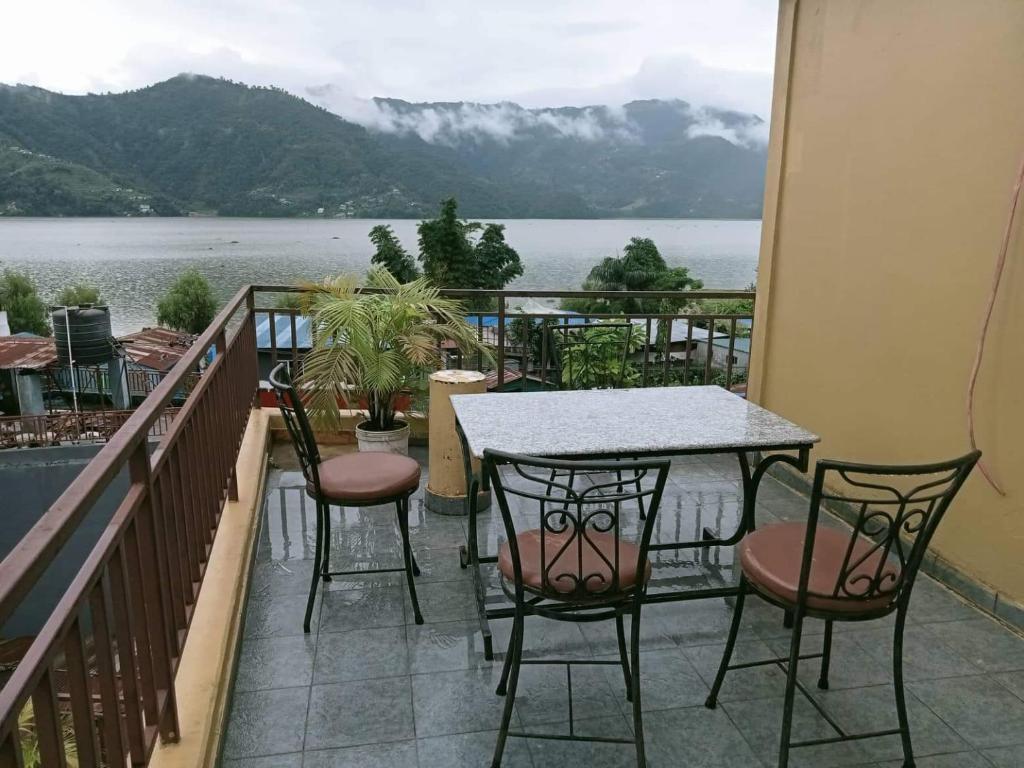 een tafel en stoelen op een balkon met uitzicht op het water bij Hotel My Dream in Pokhara