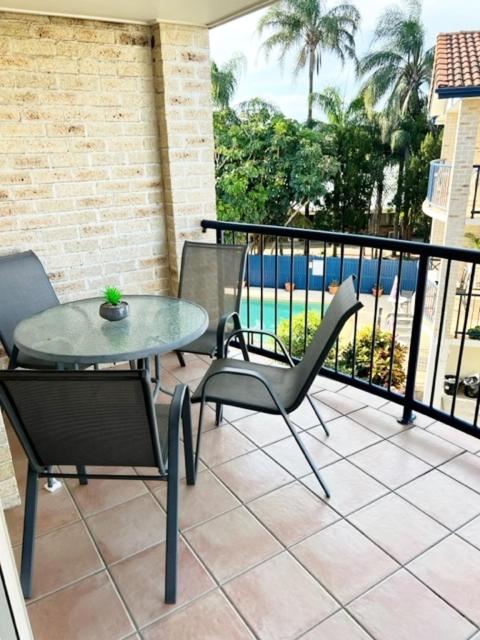 a patio with a table and chairs on a balcony at Sandy Toes in Bellara