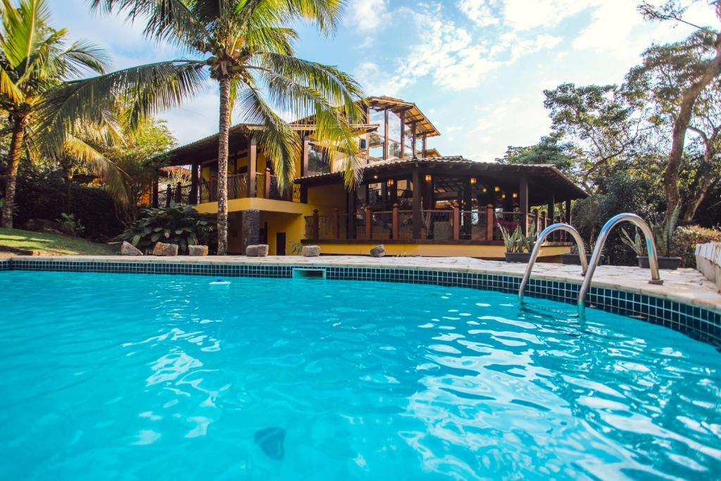 uma piscina em frente a uma casa com palmeiras em Pousada Canto da Mata Ilhabela em Ilhabela