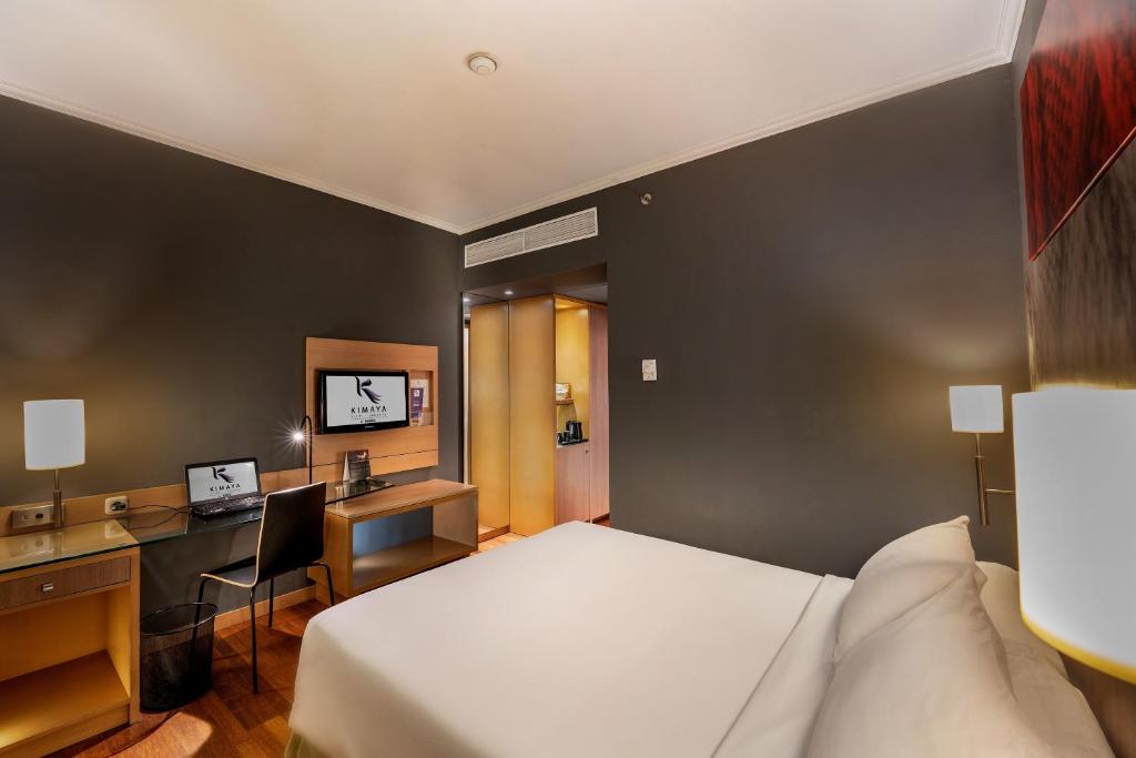 a hotel room with a bed and a desk at Hotel KIMAYA Slipi Jakarta By HARRIS in Jakarta
