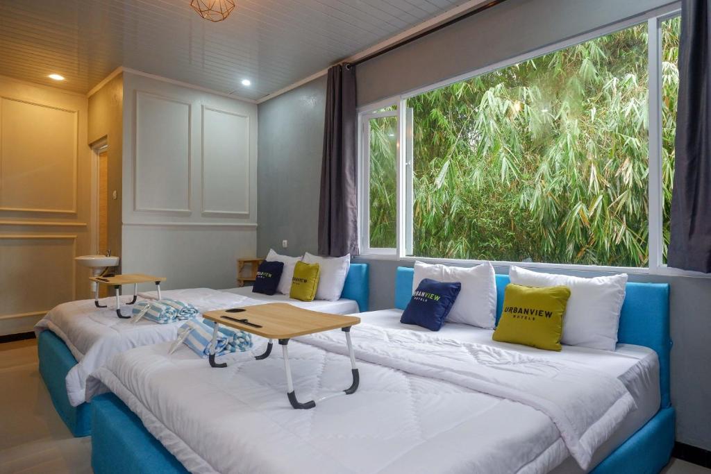 Duas camas num quarto com uma janela grande em Urbanview Hotel Umbrella Dieng by RedDoorz em Kalibeber